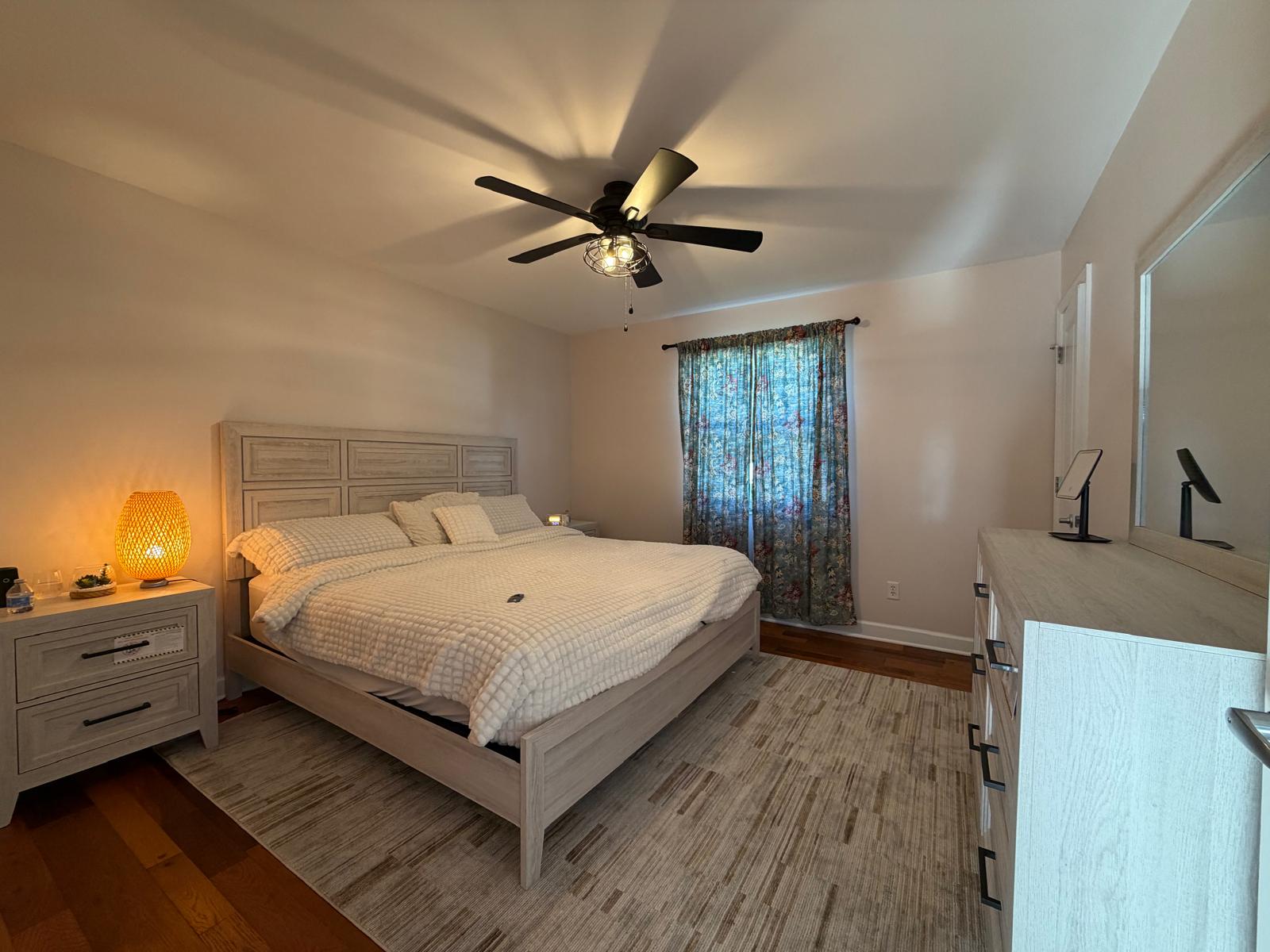King bedroom with light wood furniture and warm bedside lighting