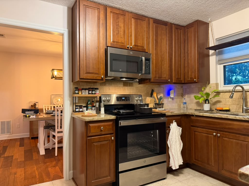 Kitchen with stove, microwave, cookware, and dining room beyond